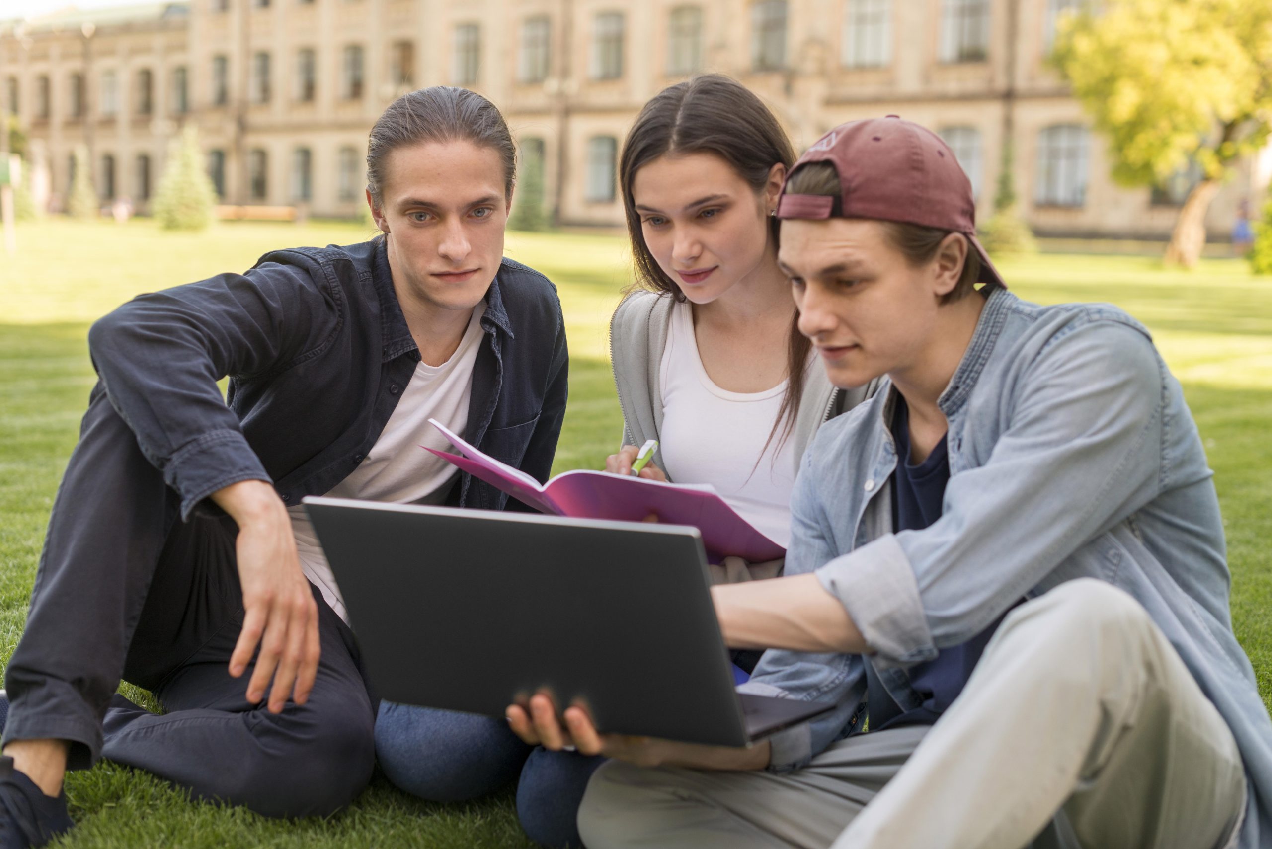 Three international university students collaborating outdoors on a laptop, symbolizing global education and talent mobility.